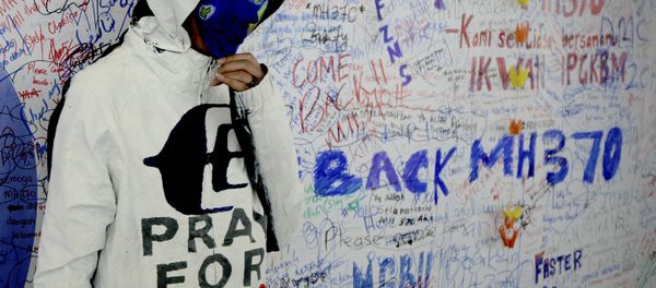 An unidentified woman wearing a mask depicting the flight of the missing Malaysia Airline, MH370, poses in front of the wall of hope at Kuala Lumpur International Airport in Sepang, Malaysia, Monday, March 17, 2014 - Sputnik International