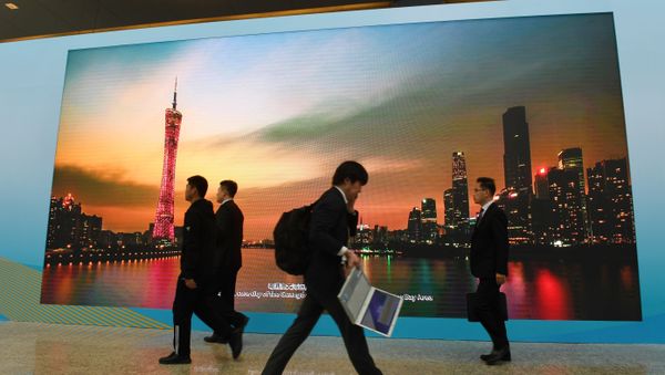 Journalists and officials walk past a screen showing a photo of the southern Chinese city of Guangzhou, at the venue of the Belt and Road Forum in Beijing on 26 April, 2019 - Sputnik International