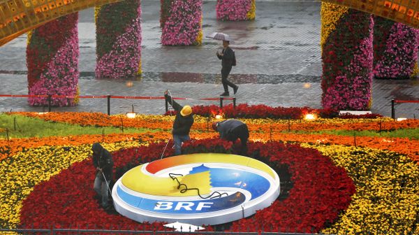 A man carrying an umbrella to shield from the rain as workers dismantle the Belt and Road Forum logo outside the media center as leaders are attending the round table summit of the Belt and Road Forum chaired by Chinese President Xi Jinping in Beijing, Saturday, April 27, 2019 A man carrying an umbrella to shield from the rain as workers dismantle the Belt and Road Forum logo outside the media center as leaders are attending the round table summit of the Belt and Road Forum chaired by Chinese President Xi Jinping in Beijing, Saturday, April 27, 2019 - Sputnik International