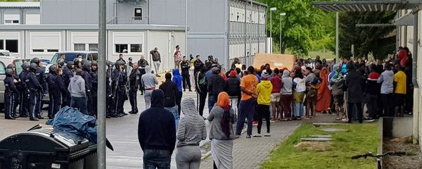 German police officers and migrants stand in front of an asylum center after a woman was found dead in the center in Regensburg, Germany, Saturday, May 11, 2019 German police officers and migrants stand in front of an asylum center after a woman was found dead in the center in Regensburg, Germany, Saturday, May 11, 2019 - Sputnik International