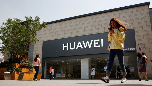 A woman looks at her phone as she walks past a Huawei shop in Beijing, China May 16, 2019 - Sputnik International