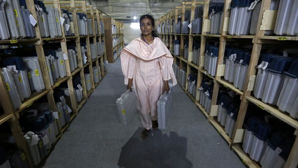 An election staff member carries Electronic Voting Machines (EVM) after collecting them from a distribution centre at an indoor stadium ahead of the seventh and last phase of general election, in Kolkata, India, May 18, 2019 - Sputnik International