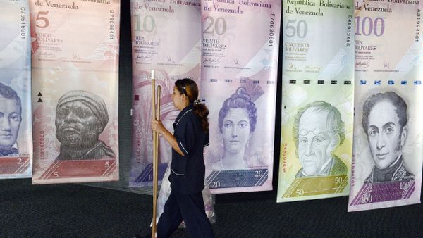 A woman walks past banners portraying the Venezuelan currency, the Bolivar, at the Venezuelan Central Bank in Caracas - Sputnik International