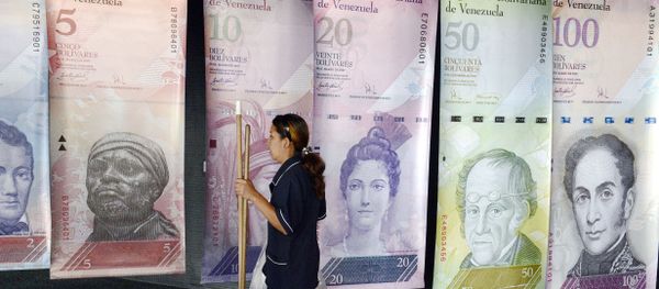 A woman walks past banners portraying the Venezuelan currency, the Bolivar, at the Venezuelan Central Bank in Caracas - Sputnik International