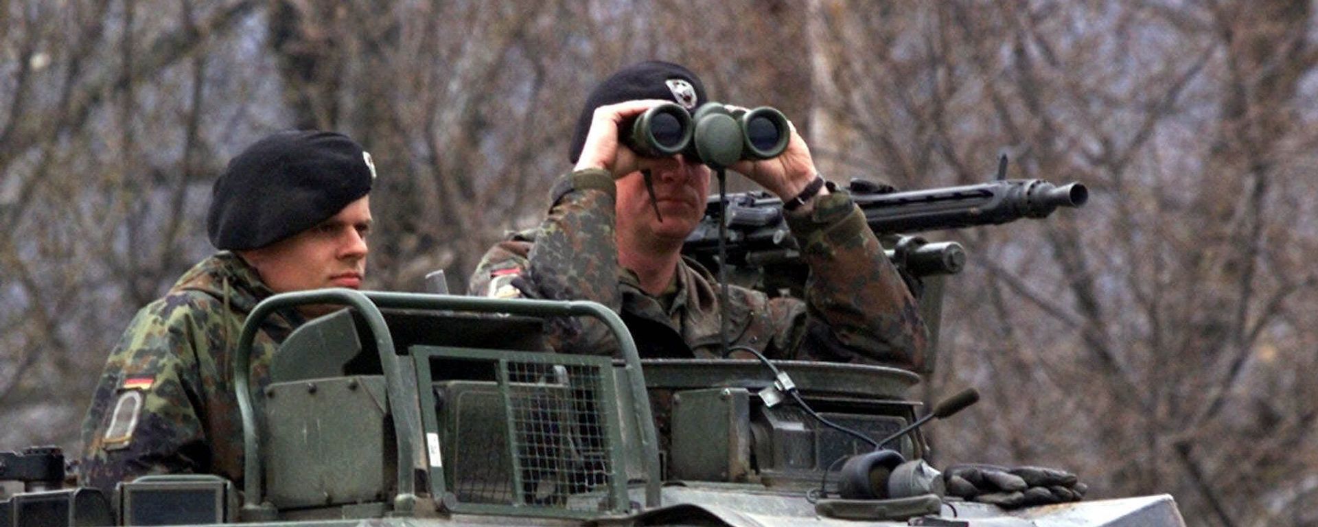 A German officer of the NATO contingent deployed in Macedonia looks through his binoculars A German officer of the NATO contingent deployed in Macedonia looks through his binoculars - Sputnik International, 1920, 08.05.2023