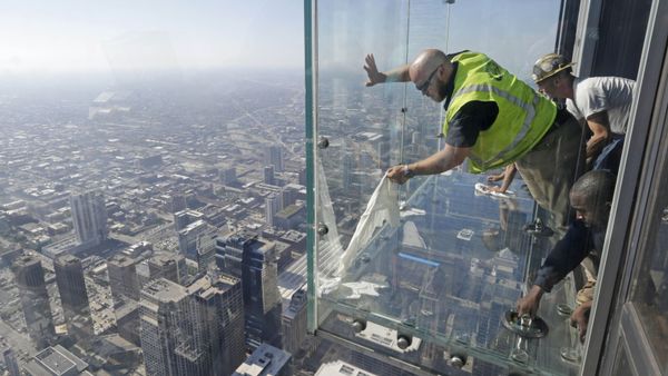 Glaziers from MTH Industries finish replacing a layer of protective coating over the glass surface on the floor of one of four transparent ledges that jut out from the 103rd floor of the Willis Tower in Chicago on Thursday, May 29, 2014. The see-through glass bays known as The Ledge were designed with a protective coating that completely covers all glass surfaces to protect against scratches. One of the coatings cracked Wednesday night when a family was standing on it. Officials say the family wasn't in danger and the coating does not affect the structural integrity of the enclosure. - Sputnik International