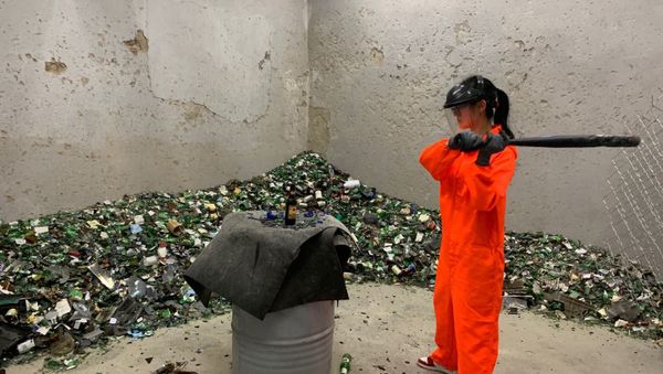 A fully-equipped woman is smashing a bottle in one of China's rage rooms - Sputnik International