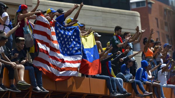Anti-government protesters hold the US national flag next to a Venezuelan national flag during the commemoration of May Day in Caracas, on May 1, 2019 after a day of violent clashes on the streets of the capital spurred by Venezuela's opposition leader Juan Guaido's call on the military to rise up against President Nicolas Maduro Anti-government protesters hold the US national flag next to a Venezuelan national flag during the commemoration of May Day in Caracas, on May 1, 2019 after a day of violent clashes on the streets of the capital spurred by Venezuela's opposition leader Juan Guaido's call on the military to rise up against President Nicolas Maduro - Sputnik International