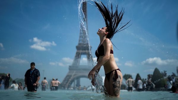A woman plays the water as she cool herself down in the fountain of the Trocadero esplanade in Paris on June 25, 2019 with the Eiffel Tower on the background - Sputnik International