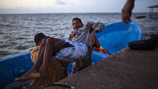 In this Sept. 4, 2018 photo, Saul Ronaldo Atiliano, 45, is carried by comrades while arriving to Puerto Lempira, Honduras, after suffering decompression syndrome while fishing for lobsters in the ocean. - Sputnik International