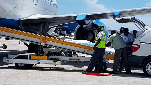 In this handout photo released by the Bahamas ZNS Network, employees oversee the arrival of the bodies of four women and three men, including billionaire coal entrepreneur Chris Cline and his daughter, at the airport in Nassau, Bahamas - Sputnik International
