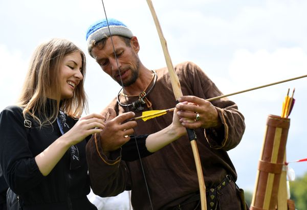 A participant shows a lady how to shoot a bow and arrow. A participant shows a lady how to shoot a bow and arrow. - Sputnik International