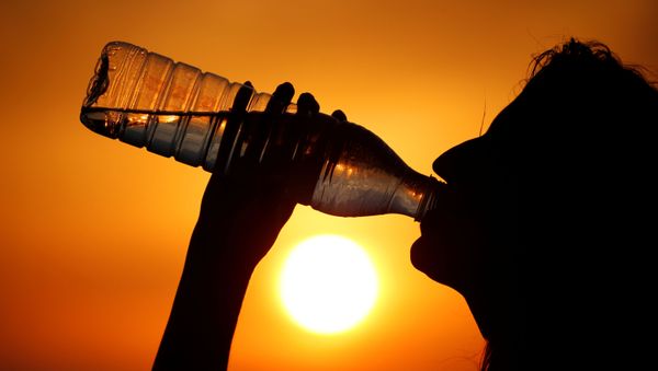 A woman drinks water during sunset, as a heatwave hits France, in Cagnicourt near Cambrai, France, June 25, 2019 - Sputnik International