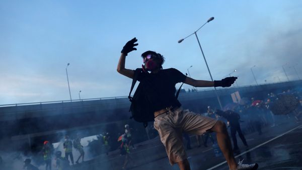 A protester reacts after throwing a tear gas canister back to the police, during a protest against police violence, near China's Liaison Office, in Hong Kong, China July 28, 2019 - Sputnik International