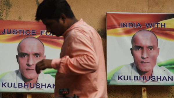 An Indian resident walks past placards with the picture of Kulbhushan Jadhav, an Indian national convicted of spying in Pakistan, in the neighborhood where he grew up, in Mumbai on July 17, 2019 - Sputnik International