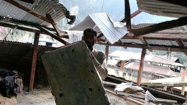 A resident shows a riddled metal suitcase as he stands under a damaged roof of a house in Salkhala village, in Neelum Valley A resident shows a riddled metal suitcase as he stands under a damaged roof of a house in Salkhala village, in Neelum Valley - Sputnik International