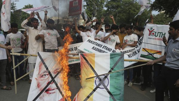 Pakistanis burn a poster of Indian Prime Minster Narendra Modi during a protest to express support and solidarity with Indian Kashmiri people in their peaceful struggle for their right to self-determination, in Lahore, Pakistan, Monday, Aug. 5, 2019. India's government has revoked disputed Kashmir's special status by a presidential order as thousands of troops patrolled and internet and phone services were suspended in the region where most people oppose Indian rule. (AP Photo/K.M. Chaudary) Pakistanis burn a poster of Indian Prime Minster Narendra Modi during a protest to express support and solidarity with Indian Kashmiri people in their peaceful struggle for their right to self-determination, in Lahore, Pakistan, Monday, Aug. 5, 2019. India's government has revoked disputed Kashmir's special status by a presidential order as thousands of troops patrolled and internet and phone services were suspended in the region where most people oppose Indian rule. (AP Photo/K.M. Chaudary) - Sputnik International