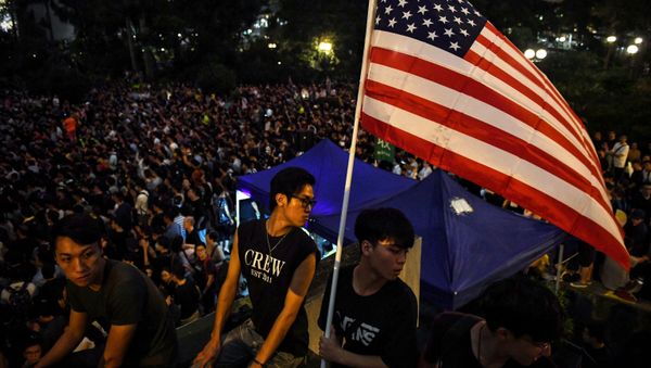 Anti-extradition bill protesters hold an American flag at a gathering at Chater House Garden in Hong Kong on August 16, 2019. - Hong Kong's pro-democracy movement faces a major test this weekend as it tries to muster another huge crowd following criticism over a recent violent airport protest and as concerns mount over Beijing's next move. - Sputnik International