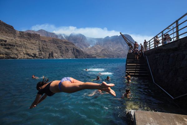People swim at the Agaete beach near the smoke from a forest fire in the village of Agaete, on the Canary Island of Gran Canaria, Spain August 20, 2019.  - Sputnik International