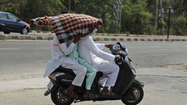 Indian men use a scarf to shield themselves from the sun as they ride a scooter on a hot summer afternoon in Hyderabad, India, Friday, May 17, 2019 - Sputnik International