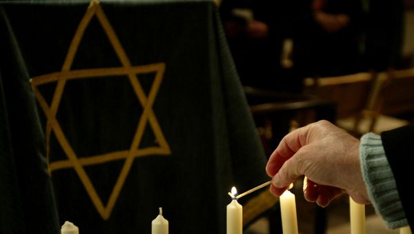 A person lights a candle during a ceremony in a synagogue A person lights a candle during a ceremony in a synagogue - Sputnik International