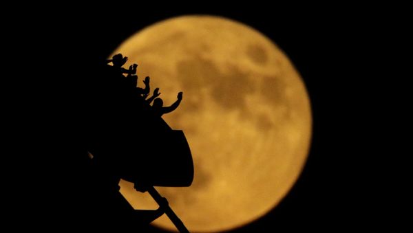 The full moon rises silhouetting roller coaster riders at the Worlds of Fun amusement park on the 50th anniversary of the Apollo 11 moon launch Tuesday, July 16, 2019, in Kansas City, Mo - Sputnik International