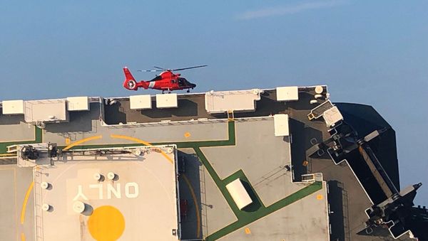 In this image released by the U.S. Coast Guard, a USCG helicopter hovers over an overturned cargo ship in St. Simons Sound, Ga., Monday, Sept. 9, 2019.  - Sputnik International