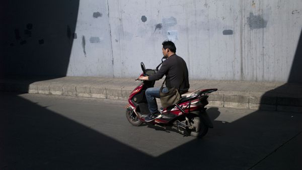 A man rides his electric scooter close to the fourth ring road in Beijing on April 20, 2016 - Sputnik International