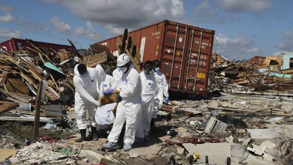 A Bahamas coroners team carries a body out of The Mudd neighborhood in the Marsh Harbor area of Abaco Island in the Bahamas in the aftermath of Hurricane Dorian, Monday, Sept. 9, 2019. Dorian, the most powerful hurricane in the northwestern Bahamas' recorded history, has killed at least 44 people in Bahamas as of Sunday, Sept. 8, according to the government. (AP Photo/Fernando Llano) - Sputnik International