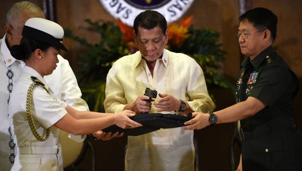 Philippine President Rodrigo Duterte (C) holds a .45 caliber handgun, one of 3,000 units handed over during a ceremonial turn-over to the military, at Malacanang Palace in Manila on July 18, 2017 - Sputnik International