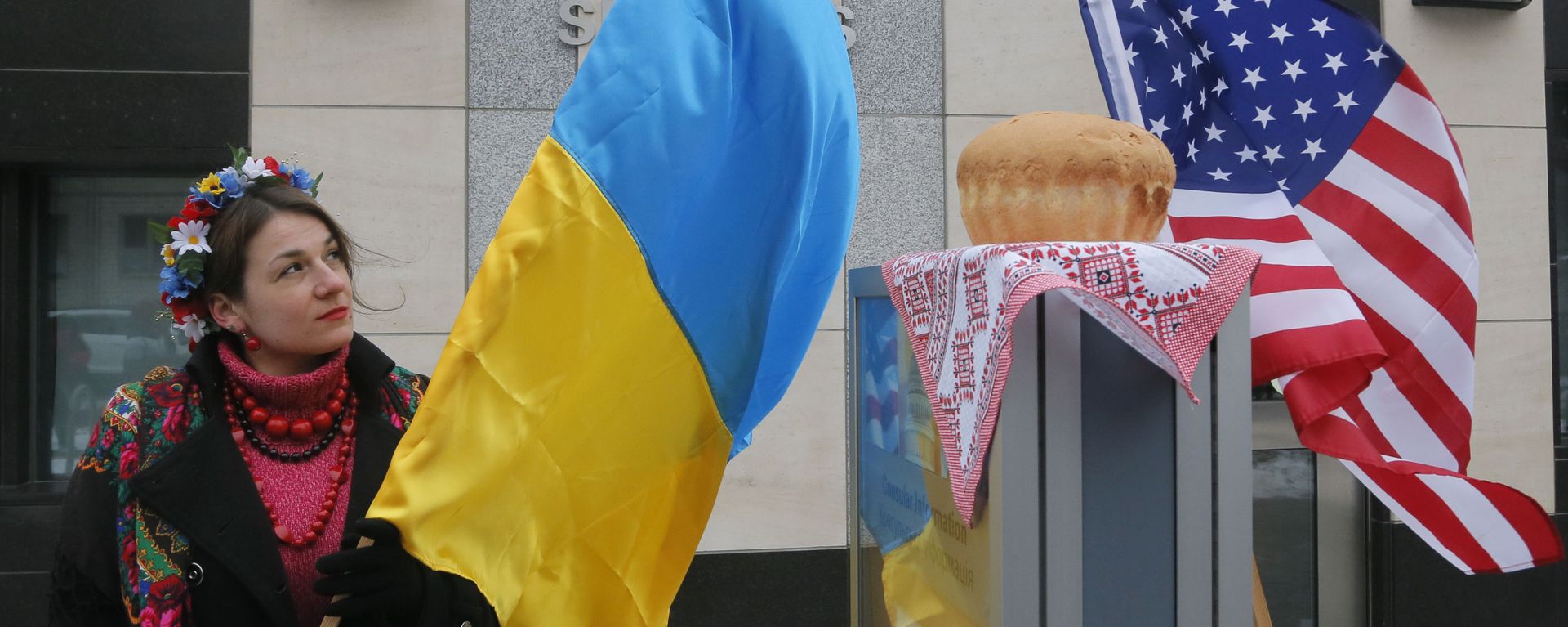 A woman holds a Ukraine flag and looks up at the traditional Ukrainian bread and salt in front of the US embassy in Kiev, Ukraine, Friday, Jan. 20, 2017, in support of Donald Trump hours before he is to be sworn in as president of the United States. A woman holds a Ukraine flag and looks up at the traditional Ukrainian bread and salt in front of the US embassy in Kiev, Ukraine, Friday, Jan. 20, 2017, in support of Donald Trump hours before he is to be sworn in as president of the United States. - Sputnik International, 1920, 14.02.2022