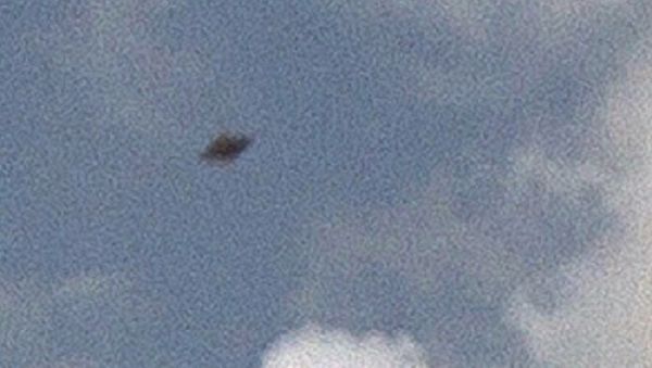 The Irish driver noticed a thick and black disk hiding in the clouds. The purported alien space ship had visible those classic saucer-shaped features - Sputnik International