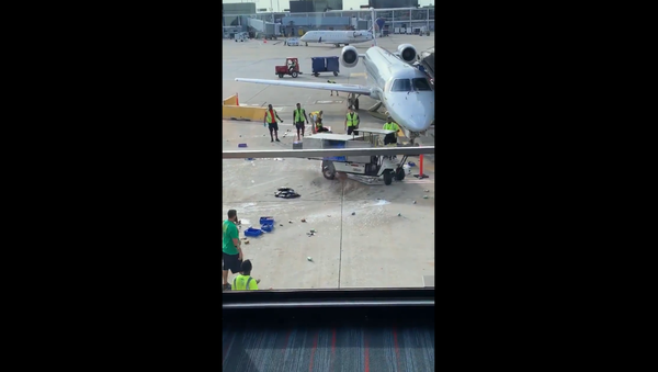 Motorized catering cart loses control, nearly strikes nose of parked plane before American Airlines worker steps in to manage incident. - Sputnik International