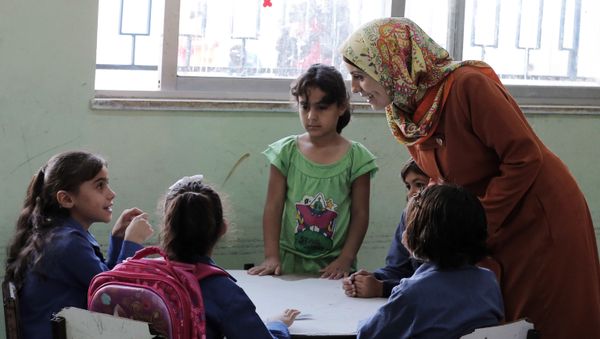 In this Thursday, Sept. 1, 2016 photo, a Jordanian teacher talks to Syrian refugee students at school in Amman, Jordan. Jordan says it is opening its schools to all Syrian refugee children, starting this week, by adding more shifts and hiring more teachers. - Sputnik International