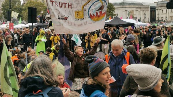 An activist holds a banner on climate change as protestors stage a sit in at a major road at Trafalgar Square in London, UK - Sputnik International