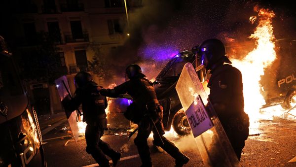 Policemen run as a police van catches fire during clashes between protestors and police in Barcelona, Spain, Wednesday, Oct. 16, 2019. Spain's government said Wednesday it would do whatever it takes to stamp out violence in Catalonia, where clashes between regional independence supporters and police have injured more than 200 people in two days. - Sputnik International