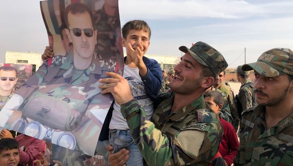 Syrian army soldiers hold placard depicting President of Syria Bashar al-Assad as Syrian government army troops rolled into Manbij, Syria, a flashpoint town west of the Euphrates River that Turkey had been aiming to capture and wrest from Kurdish control. Syrian forces moved into the area as part of a deal that has seen regime troops deploy in several Kurdish-controlled areas in Syria's north to protect the region from an assault by Turkish forces. - Sputnik International
