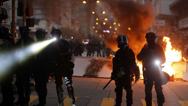 Police officers stand next to a burning barricade during an anti-government protest in Hong Kong China - Sputnik International