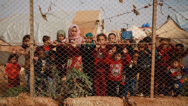 Displaced Syrian children stand behind a fence outside their tents in a camp set up near the village of Kafr Lusin, in Idlib's northern countryside near the Syria-Turkey border, on October 22, 2019. - Sputnik International