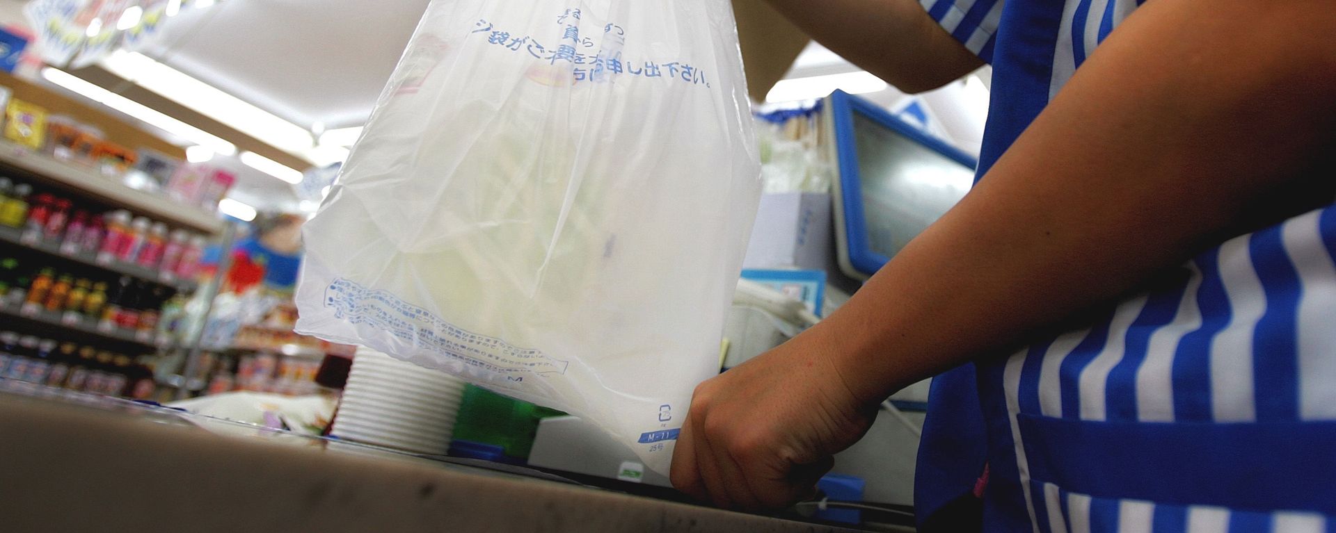A store clerk hands a plastic bag A store clerk hands a plastic bag - Sputnik International, 1920, 16.09.2020