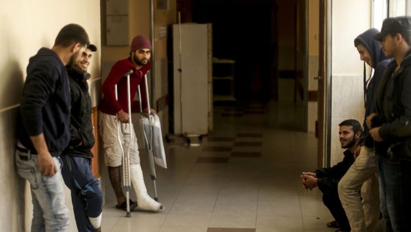 Palestinian men wounded at the Israel-Gaza border wait after receiving treatments at the Shifa Hospital in Gaza City - Sputnik International