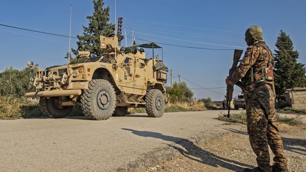 A Kurdish fighter of the Syrian Democratic Forces (SDF) watches a convoy of US armoured vehicles during a patrol of the northeastern town of Qahtaniyah at the border with Turkey, on October 31, 2019 - Sputnik International