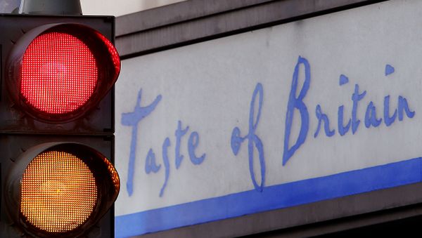Traffic lights shine red and orange in front of a small shop that offers British specialities - Sputnik International