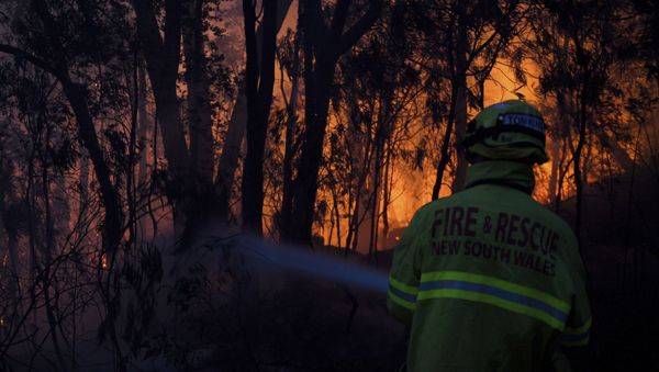 Fire and Rescue NSW firefighters conduct property protection as a bushfire burns close to homes on Railway Parade in Woodford NSW - Sputnik International