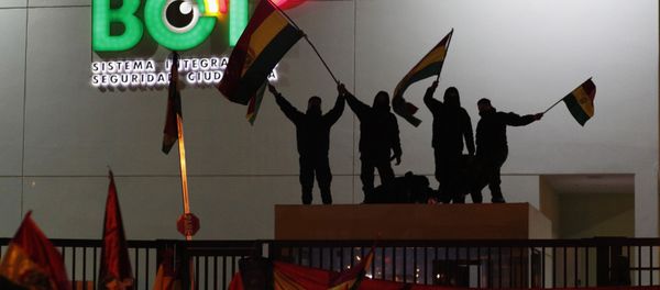 Police officers standing on the rooftop of a security booth at a police station wave Bolivian flags in front of protesters in La Paz Police officers standing on the rooftop of a security booth at a police station wave Bolivian flags in front of protesters in La Paz - Sputnik International