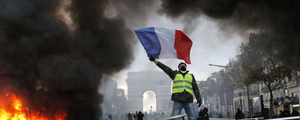 In this Nov. 24, 2018 file photo, a demonstrator waves the French flag on a burning barricade on the Champs-Elysees avenue with the Arc de Triomphe in background, during a demonstration against the rise of fuel taxes.  - Sputnik International