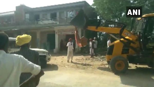 Rekha Devi, sarpanch of Mandawala village tries to climb a JCB machine in an attempt to stop anti-encroachment drive in Jalore, Rajasthan - Sputnik International