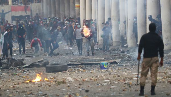 An Iraqi demonstrator throws fireworks towards Iraqi security forces during the ongoing anti-government protests in Baghdad, Iraq 23 November 2019 - Sputnik International