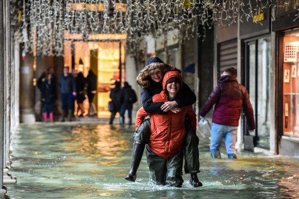 A person carries another across a flooded arcade on 24 November 2019 in Venice during the high tide Acqua Alta meteorological phenomenon. A person carries another across a flooded arcade on 24 November 2019 in Venice during the high tide Acqua Alta meteorological phenomenon. - Sputnik International