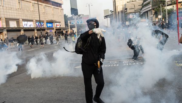 Pro-democracy protesters react after police fired tear gas during a march from the Tsim Sha Tsui district to Hung Hom in Hong Kong on December 1, 2019. - Tens of thousands of black-clad protesters flooded into the streets of Hong Kong on December 1, ending a brief election lull and demanding the government make concessions after pro-democracy candidates won a landslide victory. - Sputnik International